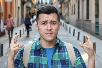 Hispanic man crossing fingers outdoors 