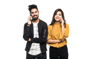 Wall Mural - Attractive indian couple talking on their smartphones on gray background