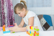 © Andreshkova Nastya - Schoolgirl girl play with educational toy on table in the children's room. Two kids playing with colorful blocks. Kindergarten educational games