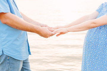 pregnant couple holding hands on beach