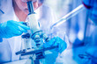 © rachaphak - Women scientist looking through microscope in laboratory. Young scientist doing some research with dropper chemical double exposure.