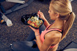© chika_milan - Top view of woman eating healthy food while sitting in a gym. Healthy lifestyle concept.