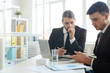 © Seventyfour - Two young businessmen in suits sitting by desk in office and brainstorming while looking for new ideas