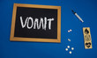 © taiga - wooden tablet on blue medical table with the word VOMIT