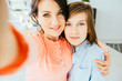 © Iryna - Mother and son at home in kitchen together taking selfie pictures on phone hugging parent to son smiling cheerful looking camera close-up.