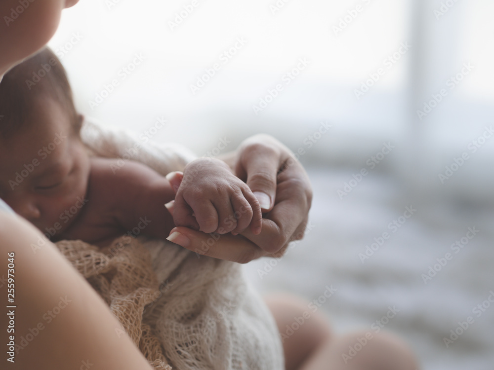 Close up Mother holding hands Asian female newborn baby  and sunlight in the morning. Cute little girl  three weeks old. Health, care, love, relationship concept. - obrazy, fototapety, plakaty 