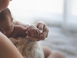Close up Mother holding hands Asian female newborn baby  and sunlight in the morning. Cute little girl  three weeks old. Health, care, love, relationship concept.