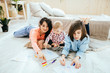 © Iryna - Cute preteen boy and toddler girl having fun on warm floor, brother, sister and their mother drawing with colored pencils, family leisure together in living room, underfloor heating.