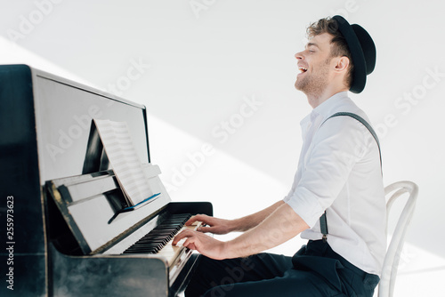 Fotografía excited pianist in stylish clothing playing piano