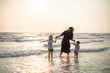 © YAMADA STOCK - Mother and children playing on the beach at the sunset time. Concept of happy family
