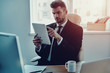 © gstockstudio - Planning his business. Thoughtful young man in formalwear using digital tablet while sitting in the office