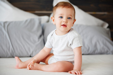 Portrait of cute baby sitting on bed