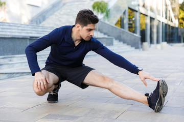 Wall Mural - Confident young sportsman doing stretching exercises