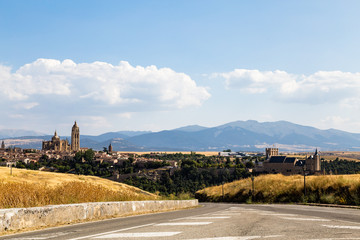 Wall Mural - Driving on the road to Segovia during summer, when all grass is yellow, burned by the sun. Castilla y Leon, Spain. Cathedral and Alcazar are visible in the picture