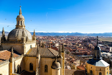 Wall Mural - Segovia, Spain – View of the dome of the Cathedral and of Segovia old town from the top of the bell tower during Winter time. The snow capped peaks of Sierra de Guadarrama are visible behind