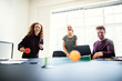 Laughing young designers playing table tennis on a boardroom tab