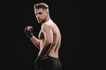 muscular strong shirtless mma fighter showing fist at camera isolated on black