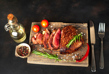 Wall Mural - Beef steak, herbs and spices on a cutting board against a background of stone