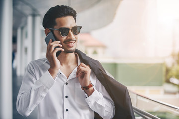 Young executive businessman using a mobile phone in the business district with skyscrapers buildings background