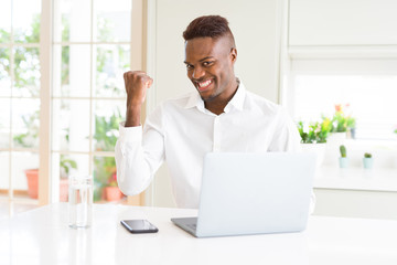 Poster - African american business man working using laptop smiling with happy face looking and pointing to the side with thumb up.