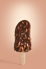 Chocolate coated ice cream on a stick on a brown background. 