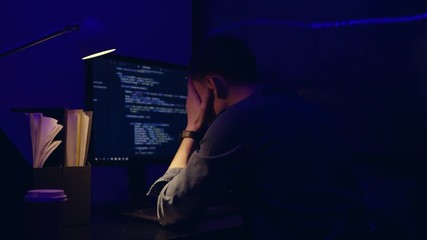 frustrated business executive working late at night in the office, he is staring at the computer screen and receiving an error message. He is very tired.