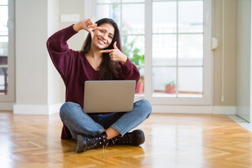 Sticker - Young woman using computer laptop sitting on the floor smiling making frame with hands and fingers with happy face. Creativity and photography concept.