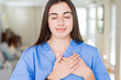 © Krakenimages.com - Beautiful young nurse woman at the clinic smiling with hands on chest with closed eyes and grateful gesture on face. Health concept.