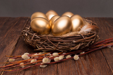 Wall Mural - Nest with golden eggs with willow on a wooden background. Easter.