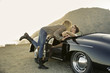 © Natalie Faye - Young woman leans over to kiss young man in convertible