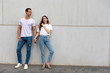 © 2Design - Happy Couple Leaning Against Wall Holding Hands wearing casual clothes in a bright day