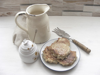 Wall Mural - Traditional russian cuisine : pancakes  with oak flakes on  shabby white wooden background with rustic milk jug, silver cultery and honey monochrome photo