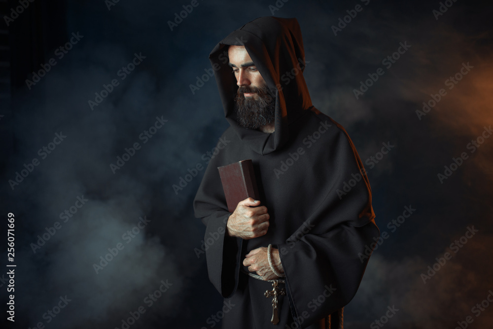 Medieval monk in robe holds spellbook in hands - obrazy, fototapety, plakaty 
