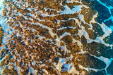 Fototapeta Do akwarium - Sea foam on small stones on the sea beach close up