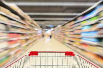 shopping cart in supermarket aisle with product shelves interior defocused blur background