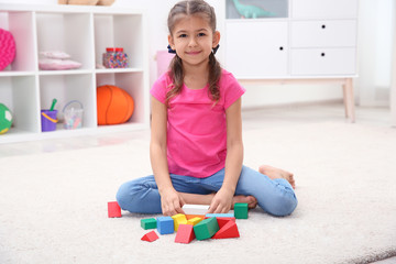 Sticker - Cute child playing with colorful blocks on floor at home