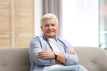 Portrait of handsome mature man on sofa indoors