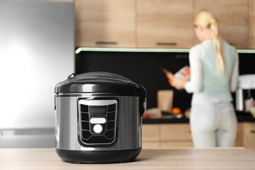 Poster - Modern multi cooker and blurred woman on background, space for text