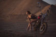 © Михаил Решетников - Red-haired woman in sexy lingerie in high heels sits on a motorcycle. Attractive red-haired girl sits on a motorcycle at sunset on the background of the industrial landscape