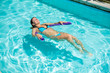 © Михаил Решетников - A young woman learns to swim in an outdoor pool using a swimming noodle.