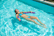 © Михаил Решетников - A young woman learns to swim in an outdoor pool using a swimming noodle.