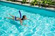 © Михаил Решетников - A young woman learns to swim in an outdoor pool using a swimming noodle.