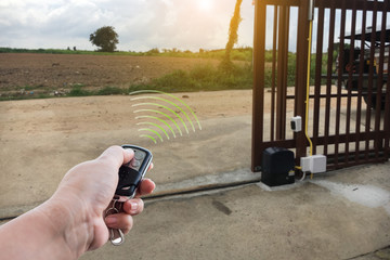 signal of remote control when person open automatic gate at house for home security system with sunl
