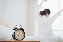 Woman Wake Up With Alarm Clock At Moring Her Stretch On Bed At Home.