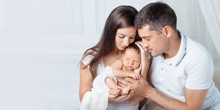 Woman And Man Holding A Newborn. Mom, Dad And Baby.  Portrait Of  Smiling Family With Newborn On The Hands. Happy Family Concept. Copy Space