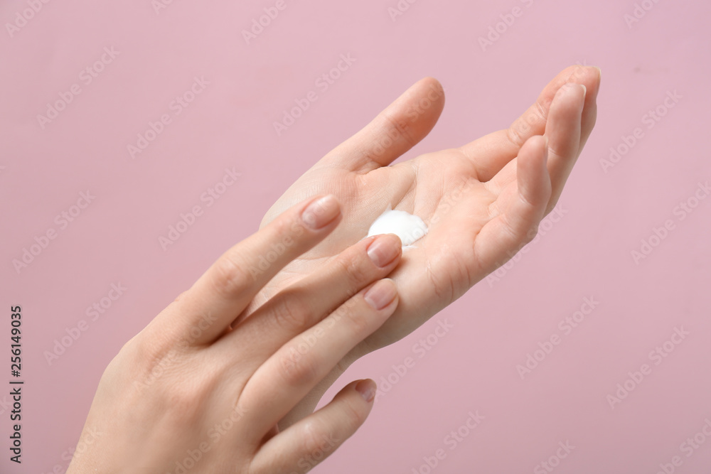 Female hands with natural cream on color background