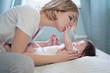 © Анна Бортникова - Happy smiling mother and baby lying on bed at home