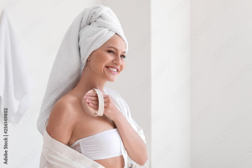 Beautiful young woman with massage brush in bathroom