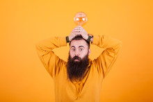 Funny Bearded Man With A Light Bulb Over His Head In Front Over Yellow Background