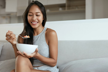 smiling woman eating healthy breakfast at home in morning